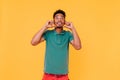 Funny carefree guy in green t-shirt looking up. Studio portrait of glad stylish man with black hair