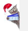 Funny cat in red christmas hat holding airline tickets. isolated on white background