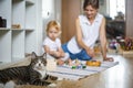 Funny cat relaxing mother and little toddler playing together self study of child Montessori method Royalty Free Stock Photo