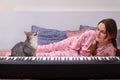 Funny cat singer amusingly sings along to a woman playing an electric piano on a home bed