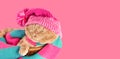 Funny cat wearing a pink knitting hat with pompom and a scarf sleeping in a basket on pink background. Horizontal banner Royalty Free Stock Photo