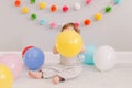 Funny Caucasian baby boy celebrating first birthday. Child kid toddler sitting on floor with colorful balloons. Celebration of Royalty Free Stock Photo