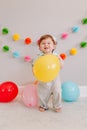 Funny Caucasian baby boy celebrating first birthday. Excited emotional child kid toddler with colorful balloons. Celebration of Royalty Free Stock Photo