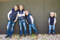 Funny Caucasian big family of three brothers and sister posing standing on growth background of wall in full growth. Equally Royalty Free Stock Photo
