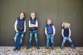 Funny Caucasian big family of three brothers and sister posing standing on growth background of wall in full growth. Equally Royalty Free Stock Photo