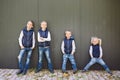 Funny Caucasian big family of three brothers and sister posing standing on growth background of wall in full growth. Equally Royalty Free Stock Photo