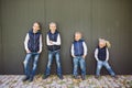 Funny Caucasian big family of three brothers and sister posing standing on growth background of wall in full growth. Equally Royalty Free Stock Photo