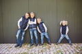 Funny Caucasian big family of three brothers and sister posing standing on growth background of wall in full growth. Equally Royalty Free Stock Photo