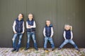 Funny Caucasian big family of three brothers and sister posing standing on growth background of wall in full growth. Equally Royalty Free Stock Photo