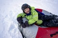 Funny Caucasian boy 5 years old rides in winter on a big inflatable cheesecake Royalty Free Stock Photo