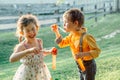 Funny Caucasian children girl and boy blowing soap bubbles in park