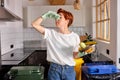 eco-friendly caucasian female in casual wear throwing spoiled fruit into waste bins cans