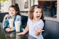 Funny Caucasian little preschool sisters siblings drink milk shakes in cafe Royalty Free Stock Photo