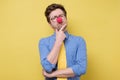 Funny caucasian man in red clown nose and yellow tie thinking with a hand in his chin Royalty Free Stock Photo