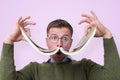 Funny caucasian male student in glasses holding book like a mustache