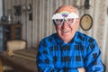 Funny caucasian old single man wearing paper party cartoon glasses with rainbow and clouds on them, smiling at the Royalty Free Stock Photo