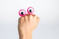 Funny character creature hiding behind female hand with googly e