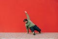Funny charismatic overweight man dancing breakdance on red wall background, wearing casual clothes. Fat guy dancing hip hop on the Royalty Free Stock Photo