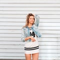 Funny charming happy young woman in fashionable summer clothes posing outdoors near a wooden vintage wall. Cheerful girl enjoys Royalty Free Stock Photo