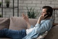 Carefree guy talk relax on sofa hold smartphone to ear Royalty Free Stock Photo