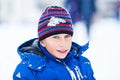 Funny cheerful boy in jacket and hat playing outdoors in winter