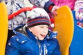 Funny cheerful boy in jacket and hat sliding