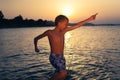 Funny cheerful little boy splashing water in sea at sunset jumping Royalty Free Stock Photo