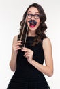 Funny cheerful woman having fun using glasses and moustache props