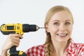 Woman pointing at her head with drill