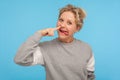Funny cheerful woman with short hair in casual sweatshirt picking nose with stupid silly face, pulling out boogers