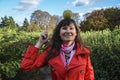 Funny cheerful young woman standing in park, smiling and looking into the camera, with green apple on her head Royalty Free Stock Photo