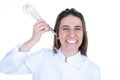 Funny chef woman with hand beater utensil in ear for fun on white background