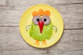 Funny chicken made of vegetables on plate and desk