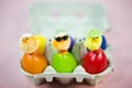 Funny chicks on colorful eggs in eggbox, pink background