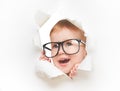 Funny child baby girl with glasses peeping through hole in an empty white paper Royalty Free Stock Photo