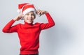 Funny child boy holds listening to Christmas music with Santa Claus hat on white background with copy space. Generation Royalty Free Stock Photo