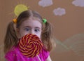 Funny child with candy lollipop, happy little girl eating big sugar lollipop, kid eat sweets. Royalty Free Stock Photo