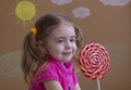 Funny child with candy lollipop, happy little girl eating big sugar lollipop, kid eat sweets. Royalty Free Stock Photo