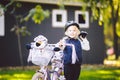 Funny child Caucasian girl blonde in a bicycle helmet near a purple bike with a basket in outside the park on a green Royalty Free Stock Photo