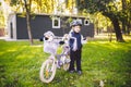 Funny child Caucasian girl blonde in a bicycle helmet near a purple bike with a basket in outside the park on a green Royalty Free Stock Photo