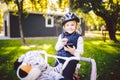 Funny child Caucasian girl blonde in a bicycle helmet near a purple bike with a basket in outside the park on a green lawn grass Royalty Free Stock Photo