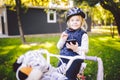 Funny child Caucasian girl blonde in a bicycle helmet near a purple bike with a basket in outside the park on a green lawn grass Royalty Free Stock Photo