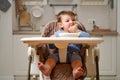 A funny child is eating a grated apple with his mouth full while sitting o Royalty Free Stock Photo