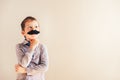 Funny child with fake mustache gesturing like an adult man, maturity and business concept