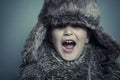 Funny child with fur hat and winter coat, cold concept and storm Royalty Free Stock Photo