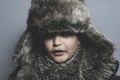 Funny child with fur hat and winter coat, cold concept and storm Royalty Free Stock Photo