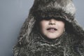 Funny child with fur hat and winter coat, cold concept and storm Royalty Free Stock Photo