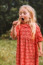 Funny child girl blowing dandelion walking outdoor family lifestyle 4 years old kid playing in the garden