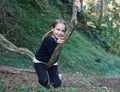 Funny child girl climbing a tree in the garden. Active kid playing outdoors. Portrait of cute young girl sitting on the branch Royalty Free Stock Photo