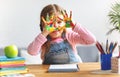 Funny child girl draws laughing shows hands dirty with paint Royalty Free Stock Photo